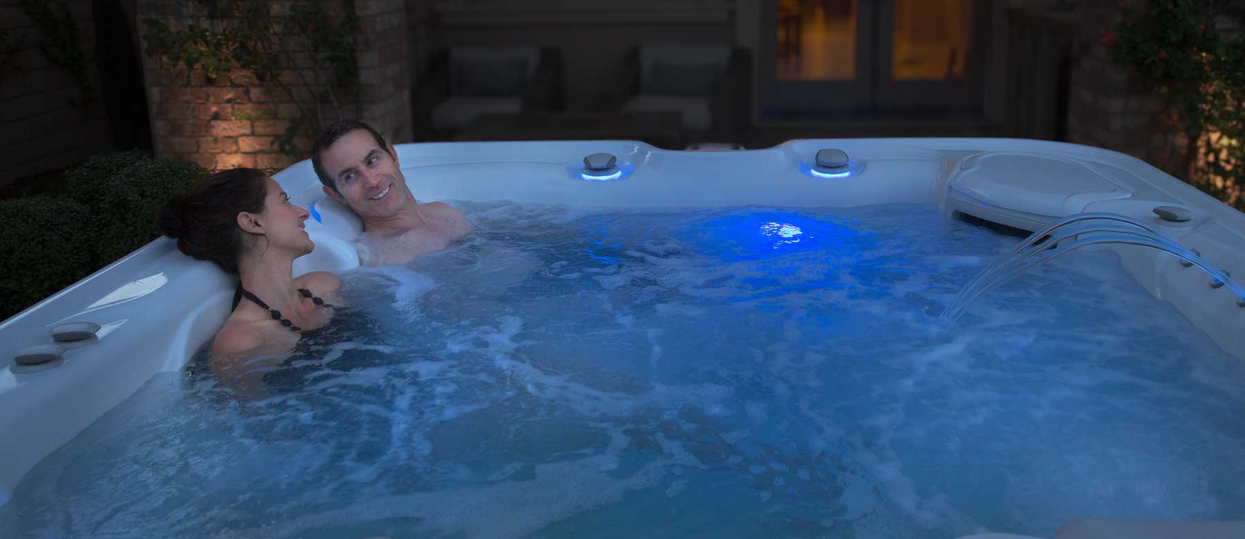 A couple in a hot tub in late evening