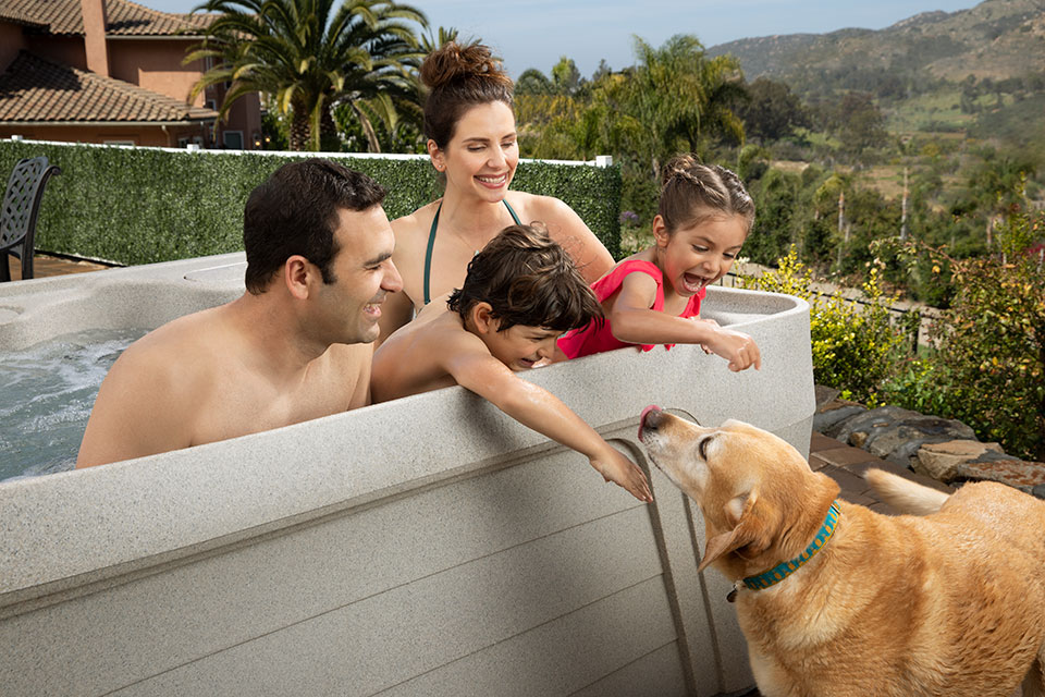 family greeted by dog in hot tub