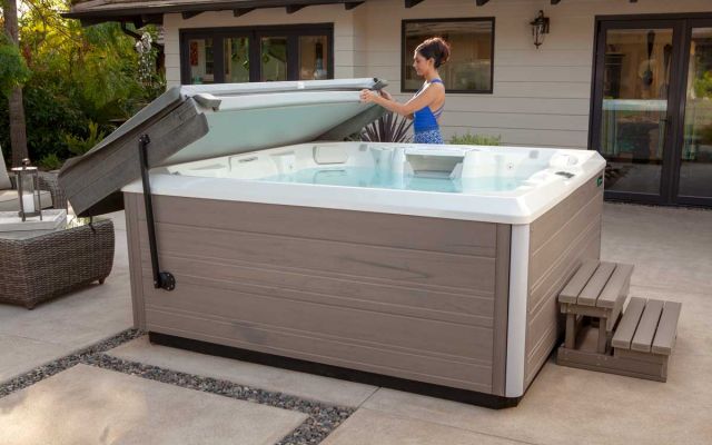 A woman opening the cover of a Limelight Pulse hot tub