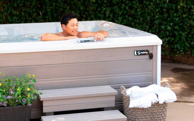 A man in a Limelight Flair hot tub, using the control pad