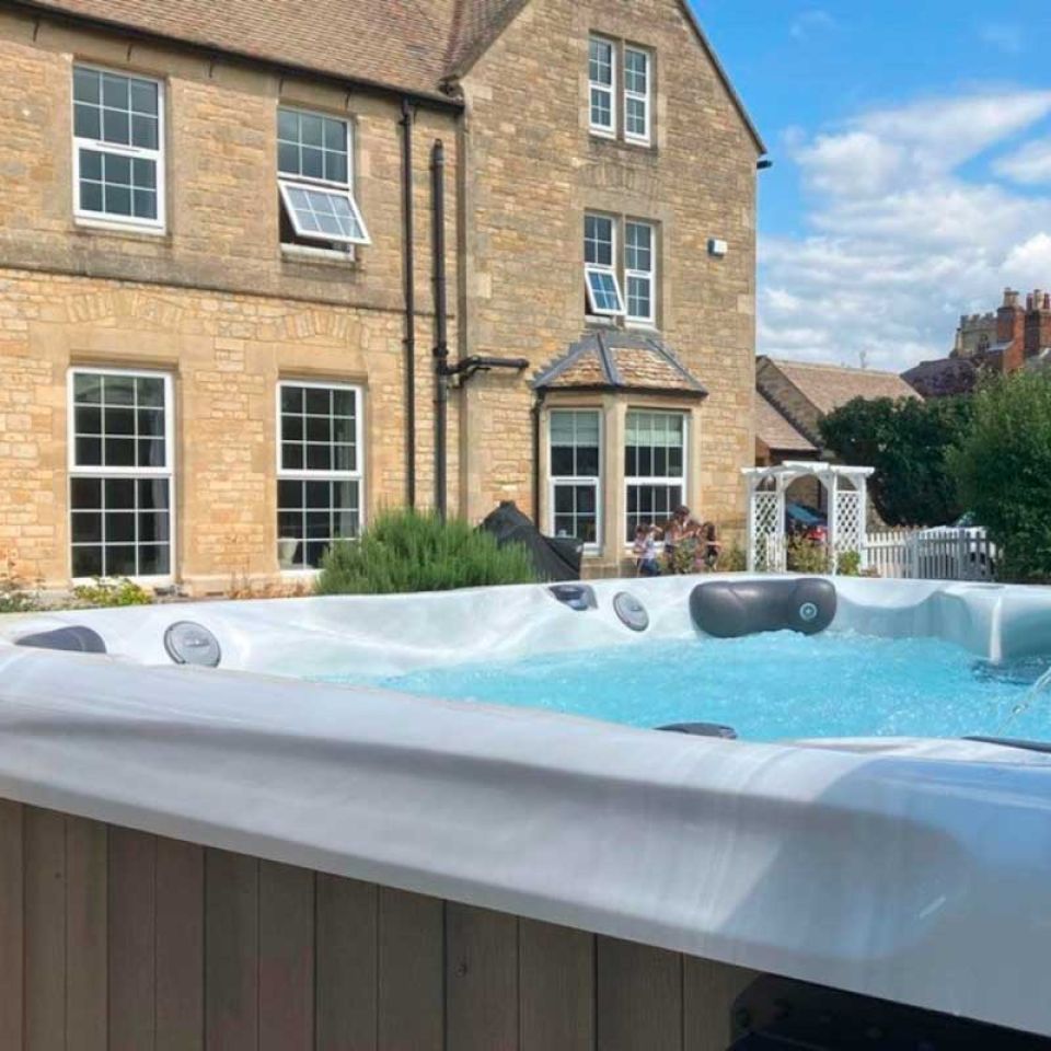 A hot tub in the back garden of a period stone house on a summer afternoon