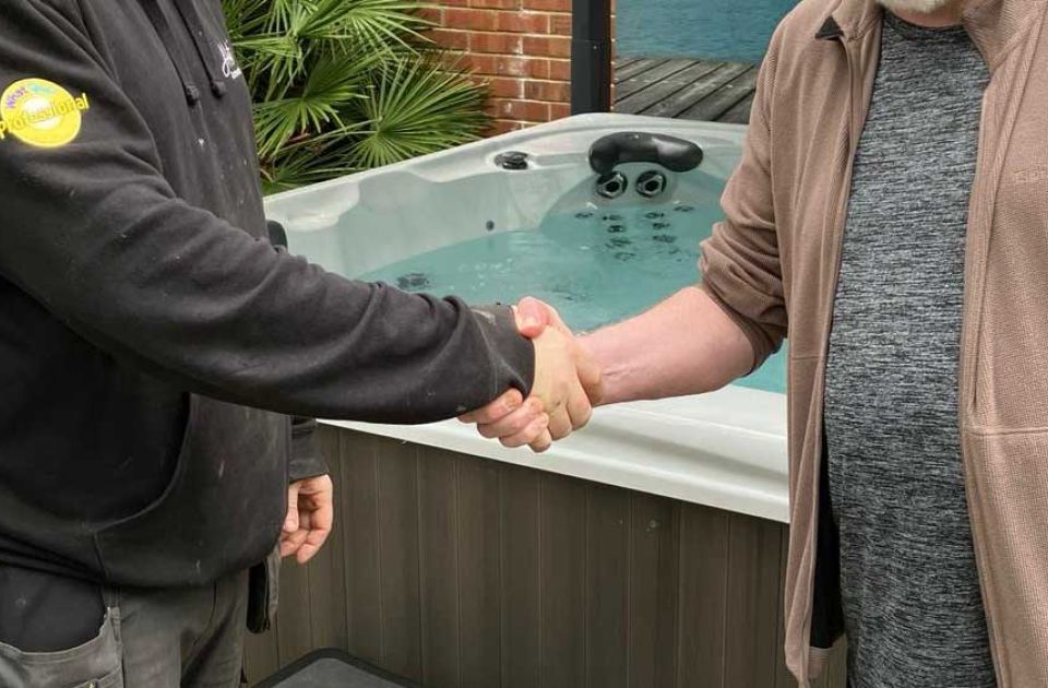 A hot tubs oxfordshire technician and a customer shaking hands in front of a filled hot tub