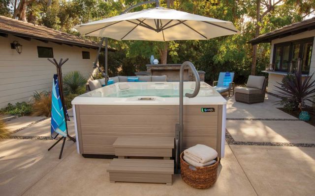 An outdoor paved area housing a Limelight Pulse hot tub and a large parasol