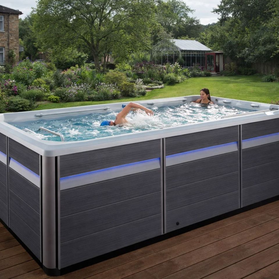 A couple in a swim spa on decking in. UK suburban garde