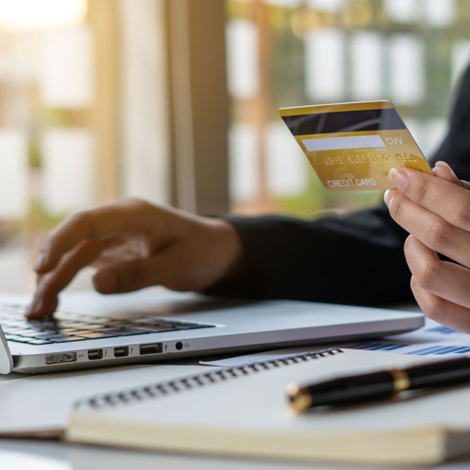 Laptop user holding a credit card while typing in details