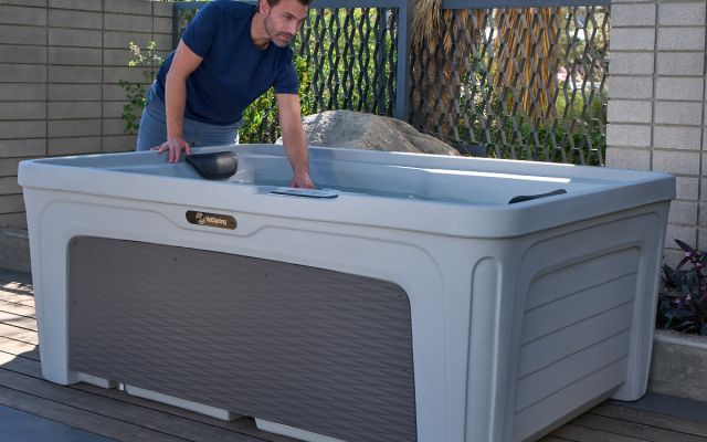 A man checking the temperature of the water in a Freeflow Mini hot tub