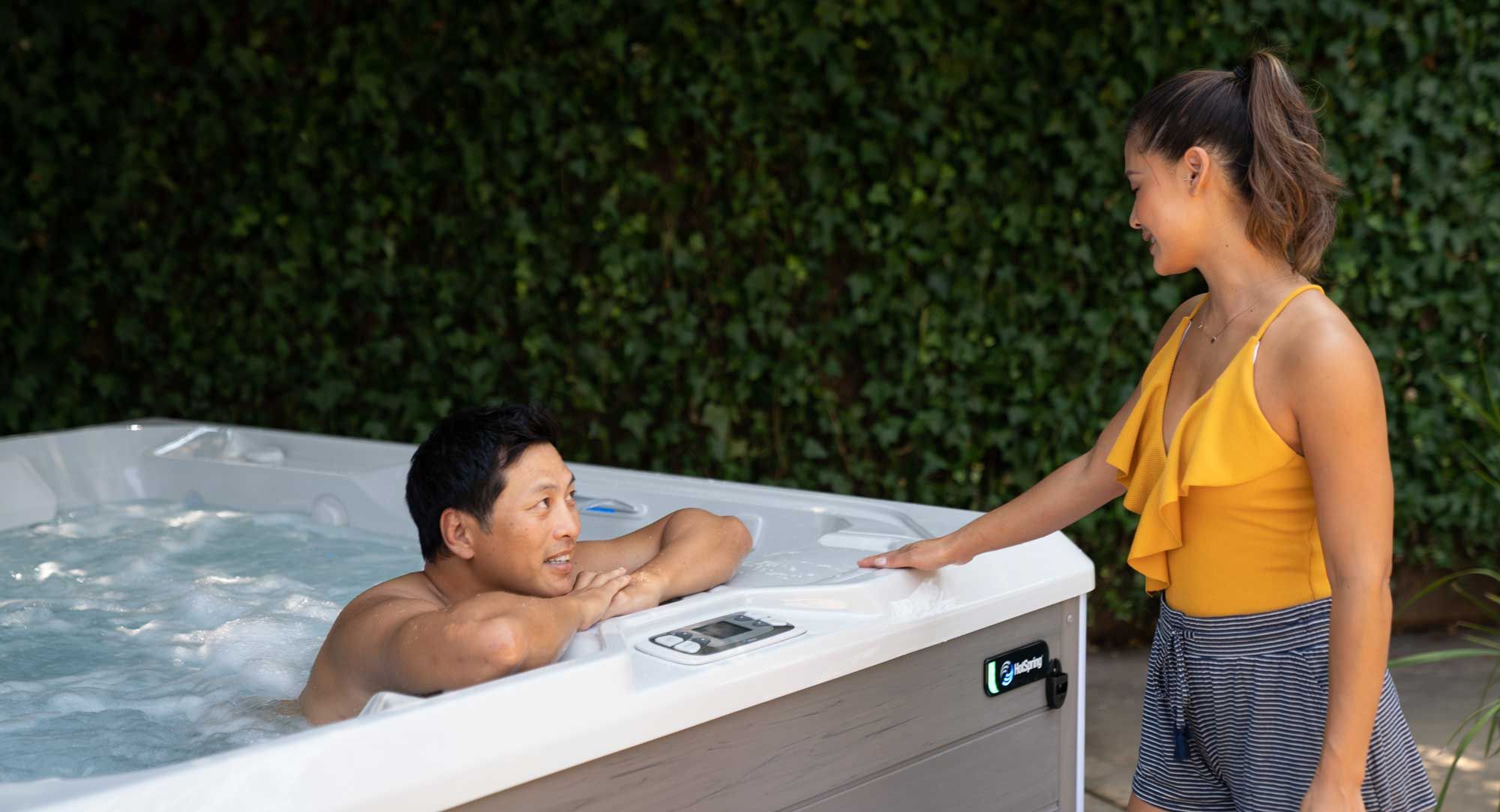 Man in hot tub talking to women outside