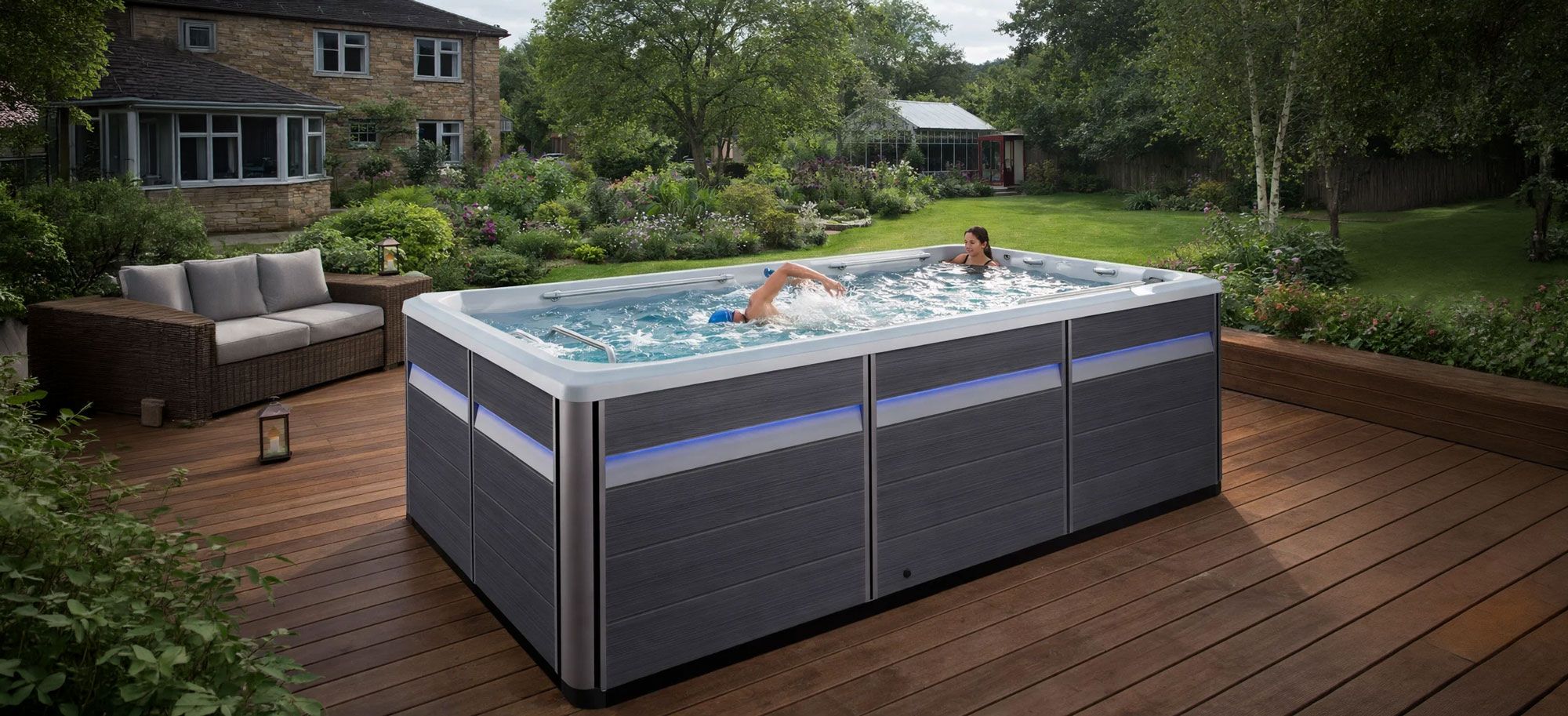 A couple in a swim spa on decking in. UK suburban garde