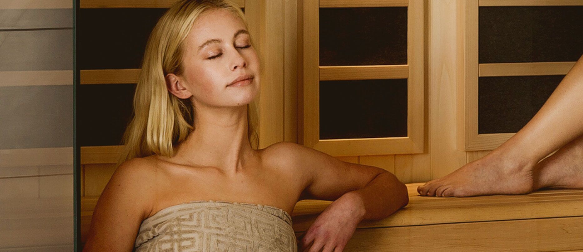 Blonde woman in a towel enjoying a sauna