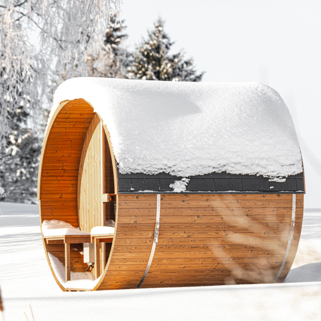 A snow-capped Hekla Barrel 210 sauna in a snowy landscape