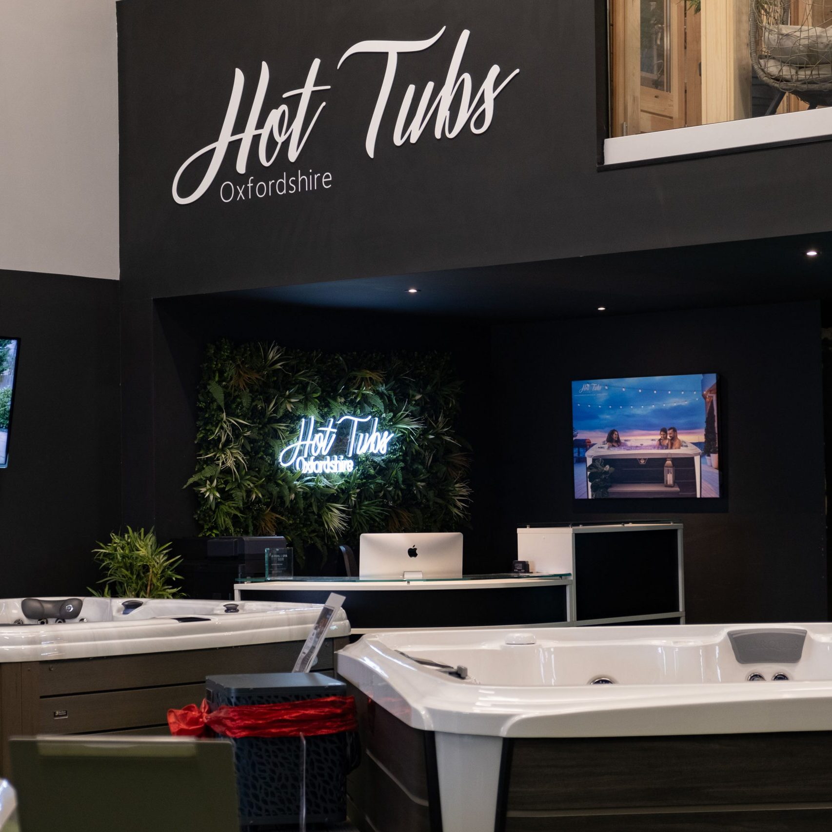 A view inside the Hot Tubs Oxfordshire showroom showing three hot tubs with te reception desk in the background
