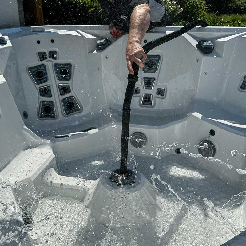 A vacuum hose inserted into the central floor jet of a hot tub and set in reverse so it is blowing all the jets clear. Water is captured mid air in bubbles and globules.