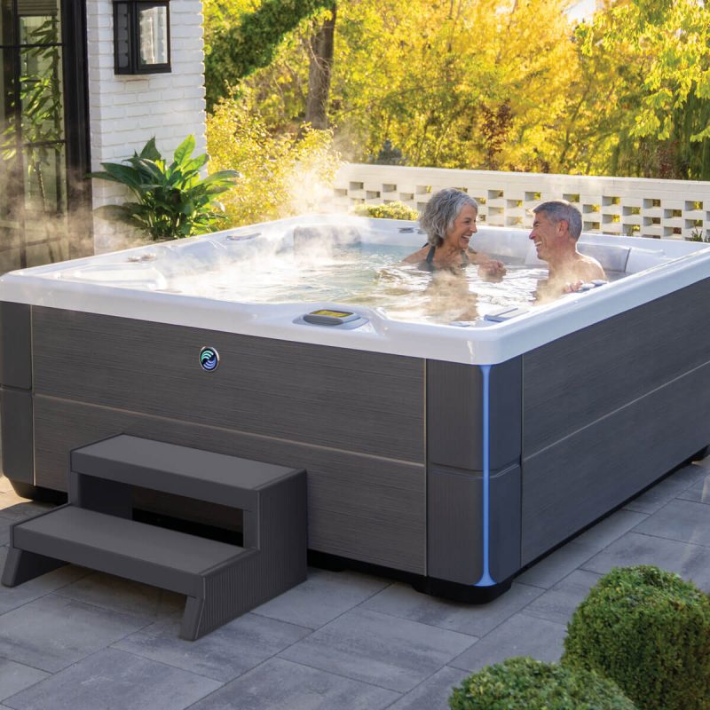 A couple enjoying time together in an Aria hot tub, which is filled and steam is rising from the ater